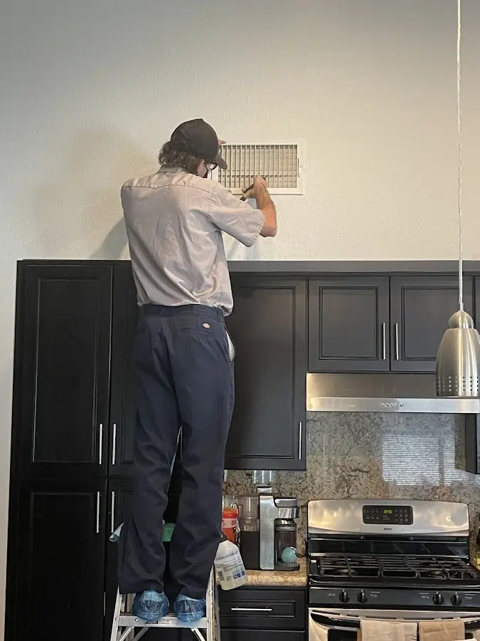 Technician inspecting an air vent during HVAC service in Lenox